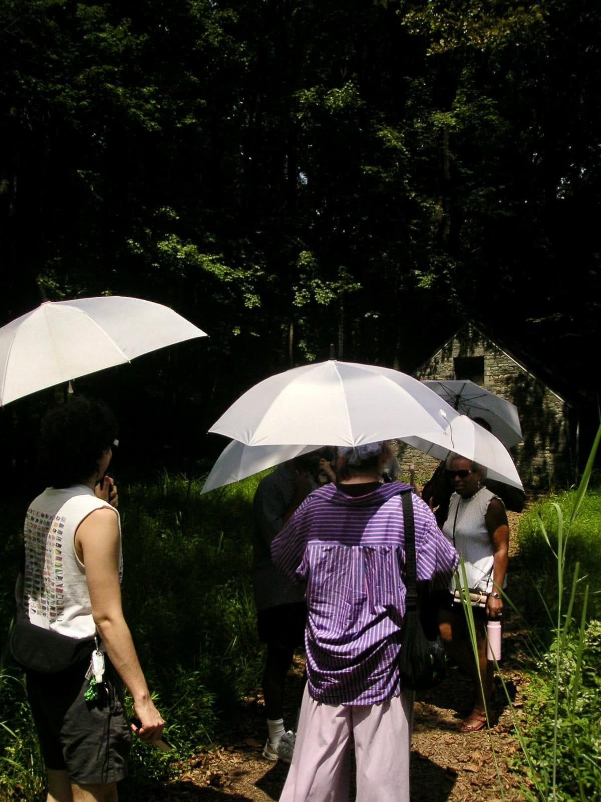 Ours members under white umbrellas on a field trip to Glenstone