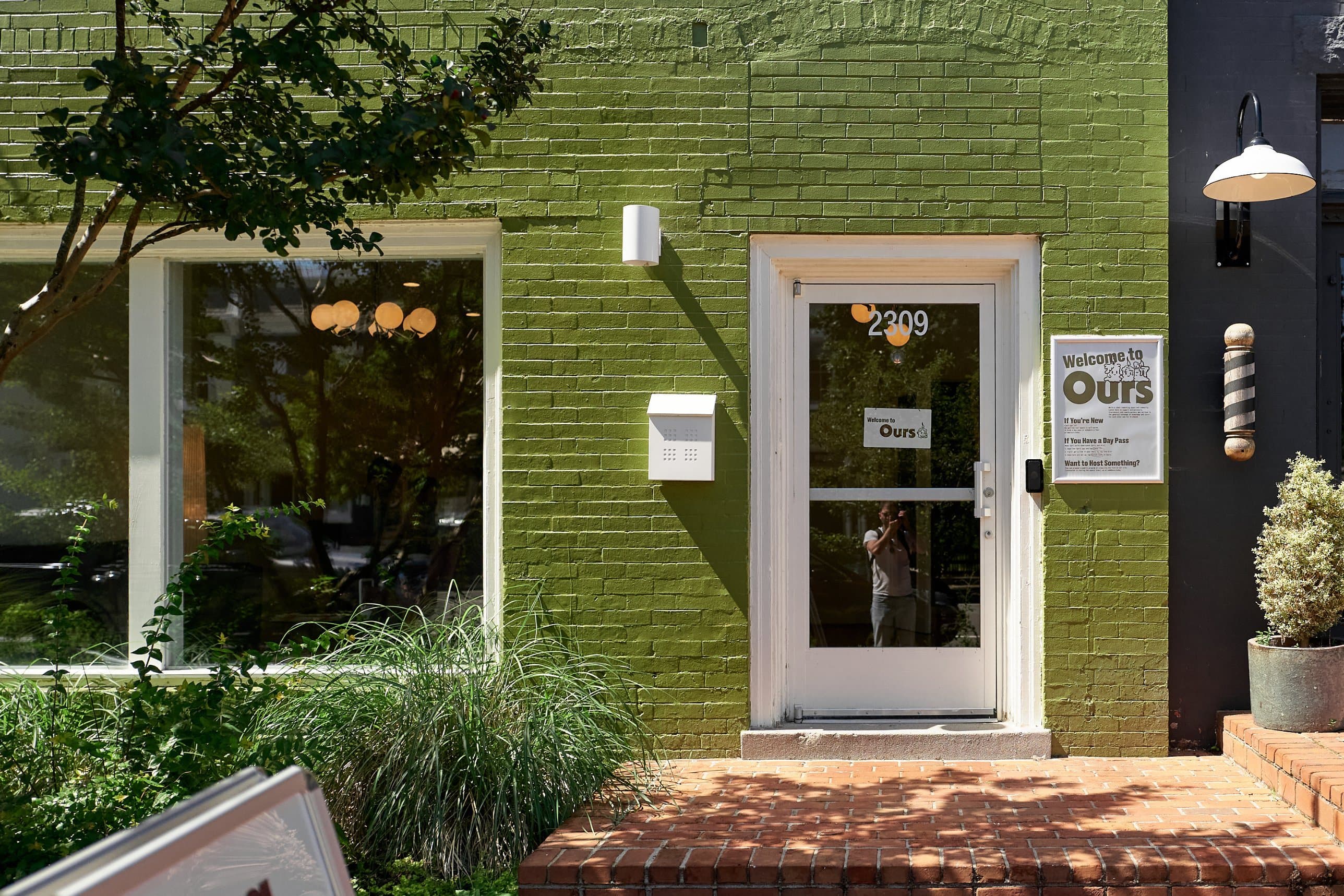 The green brick front of Ours at 2309 West Main Street, with the white front door and a Welcome to Ours sign.