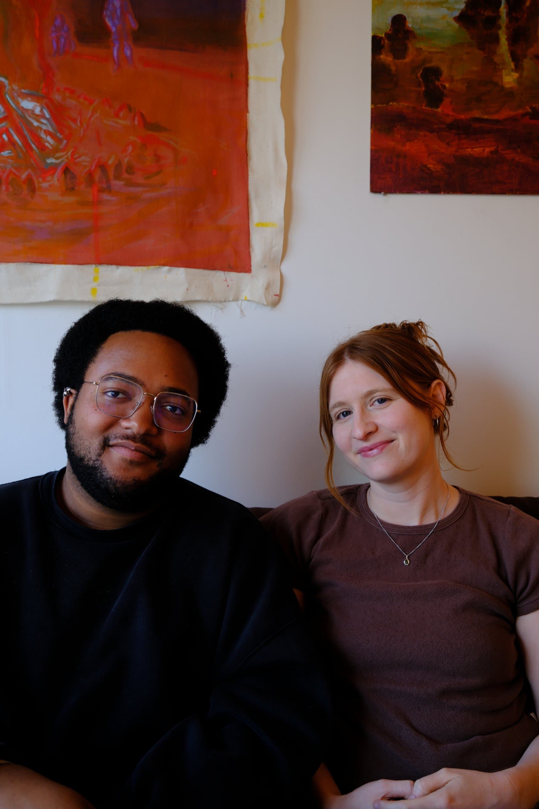 Sam Taylor and Liza Pittard on a couch at Ours, under two paintings