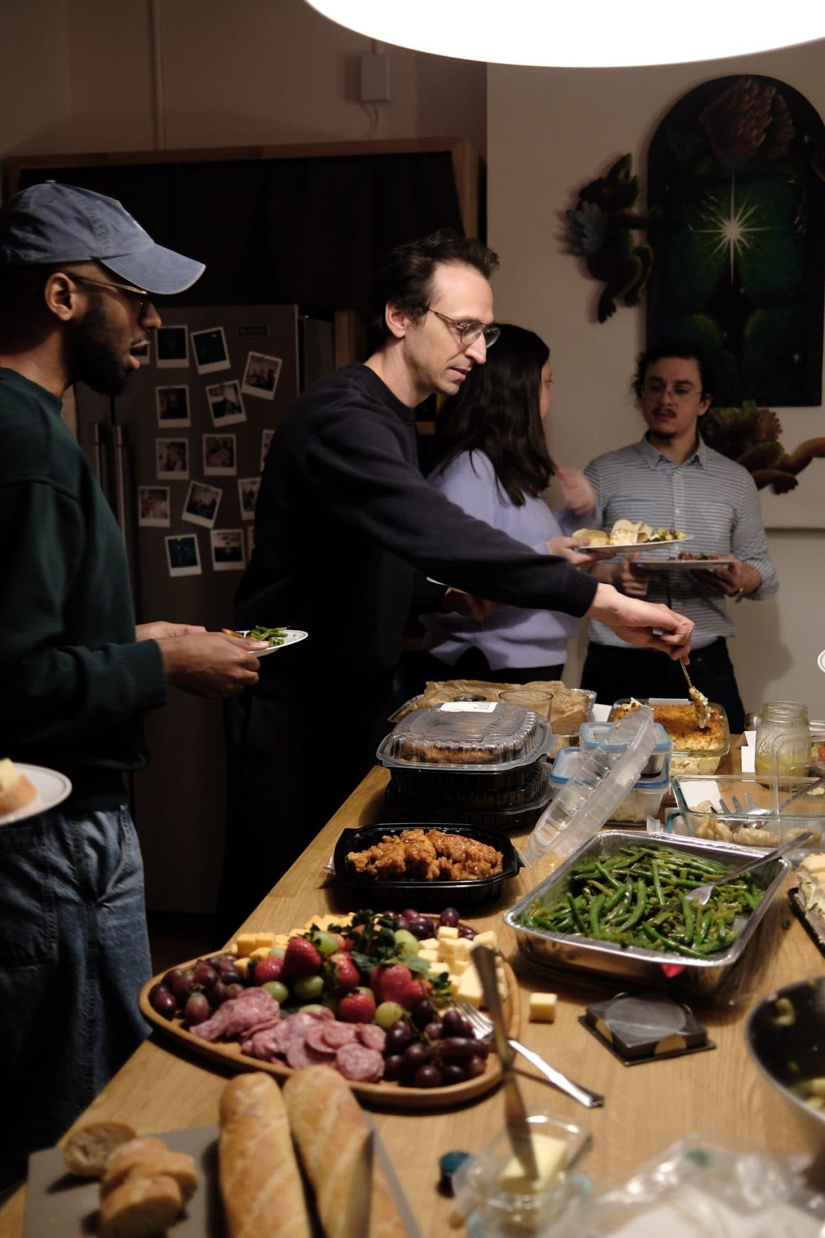 Members filling their plates at a town hall potluck in the Ours kitchen