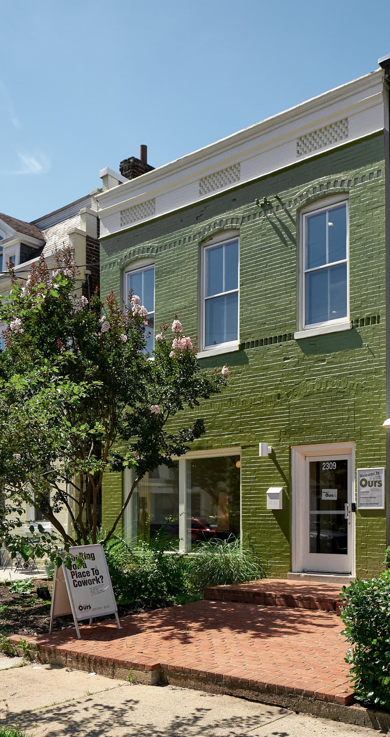 Ours from West Main Street, a green brick building with a white door